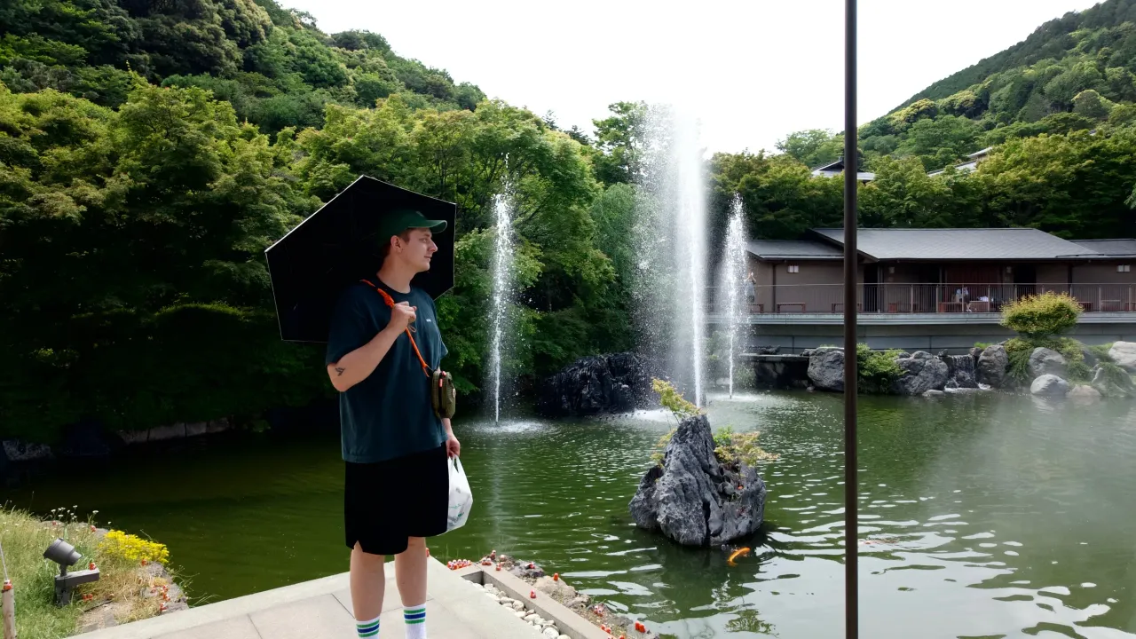 Wide Portrait of Elias Lindblad with an umbrella in front of a pool of water.